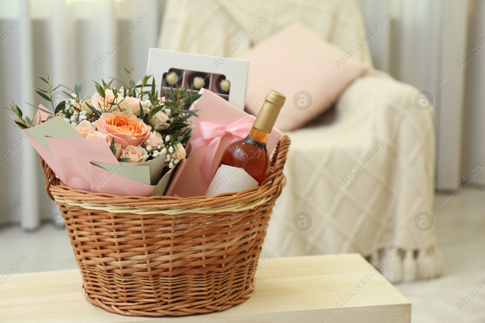 Photo of Wicker basket with gifts on table indoors. Space for text