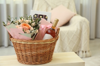 Wicker basket with gifts on table indoors. Space for text