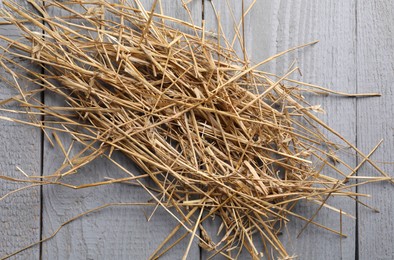 Pile of dried straw on grey wooden table, top view