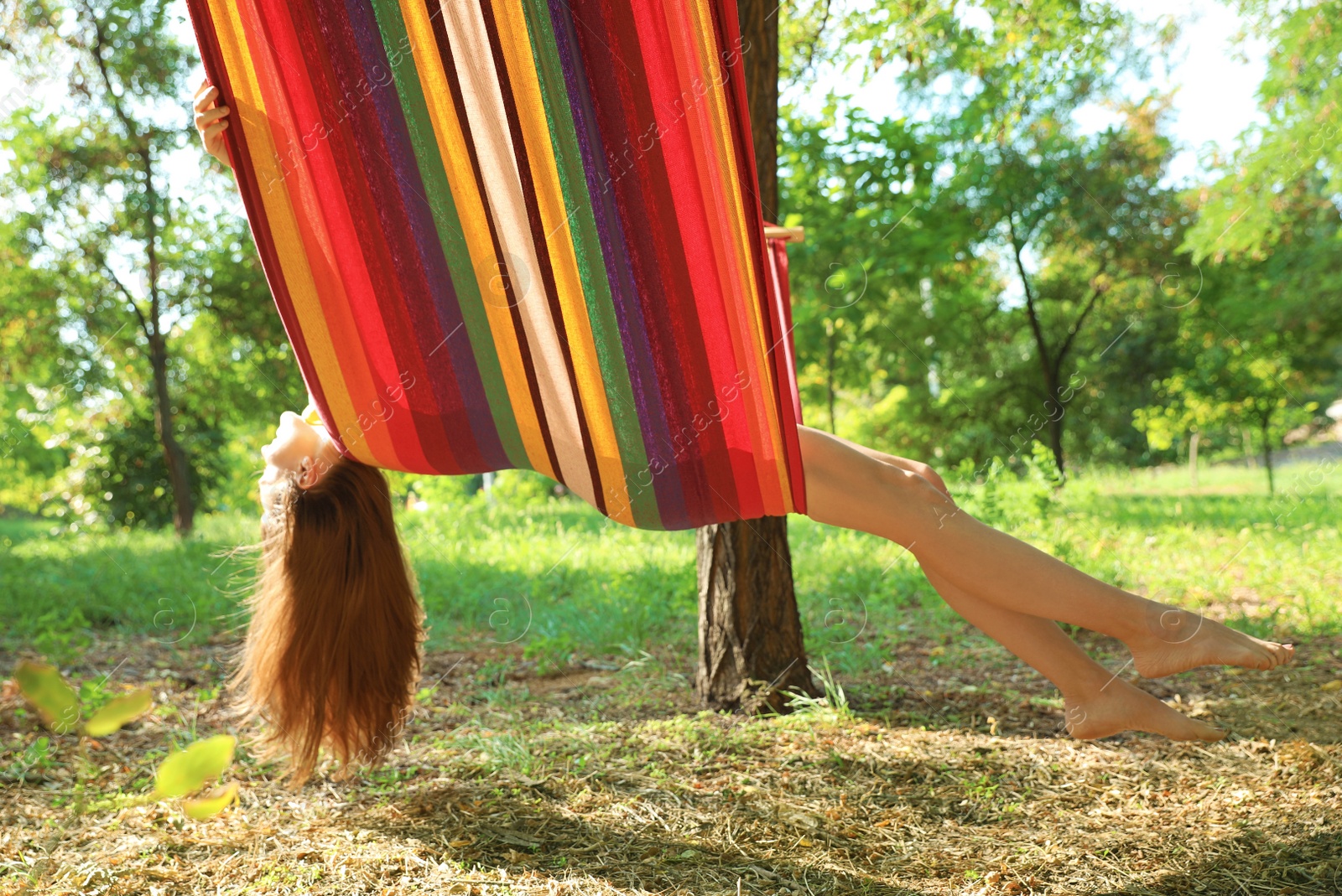 Photo of Happy young woman resting in comfortable hammock at green garden