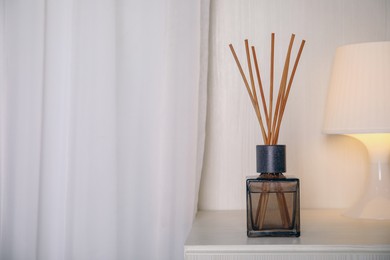 Photo of Aromatic reed freshener on bedside table indoors, space for text
