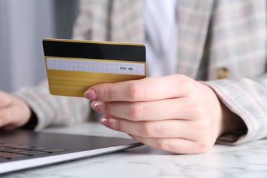 Online payment. Woman with laptop and credit card at white marble table, closeup