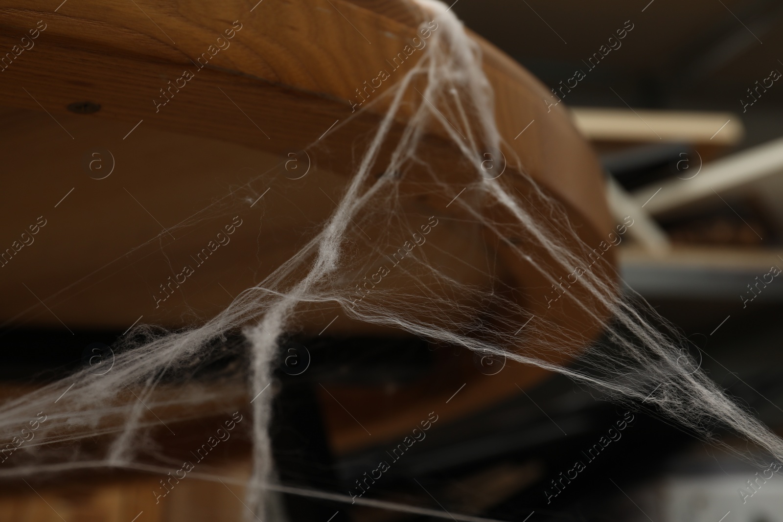 Photo of Old cobweb on wooden table indoors, closeup