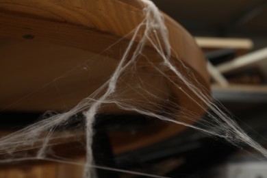 Old cobweb on wooden table indoors, closeup