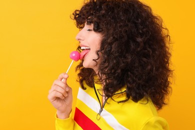 Beautiful woman with lollipop on yellow background