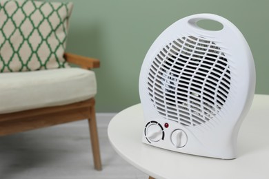 Electric fan heater on white table indoors. Space for text