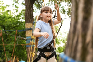 Little girl climbing in adventure park. Summer camp