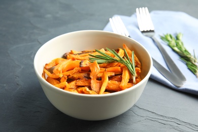 Bowl with baked sweet potato slices served on grey table