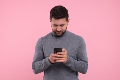 Photo of Happy man using smartphone on pink background