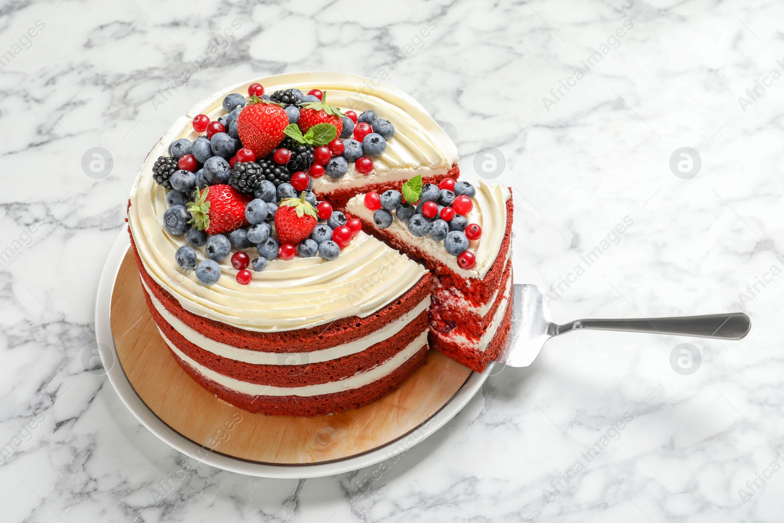 Photo of Delicious homemade red velvet cake with fresh berries on marble table