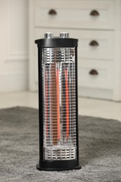 Photo of Modern infrared heater on carpet in room