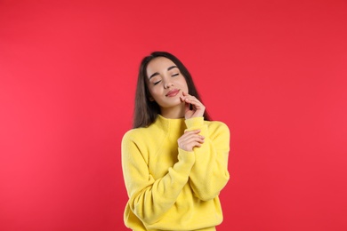 Photo of Beautiful young woman wearing yellow warm sweater on red background