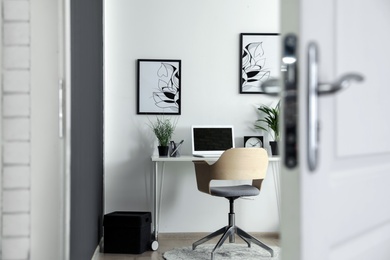 Photo of Stylish home office interior, view through open door
