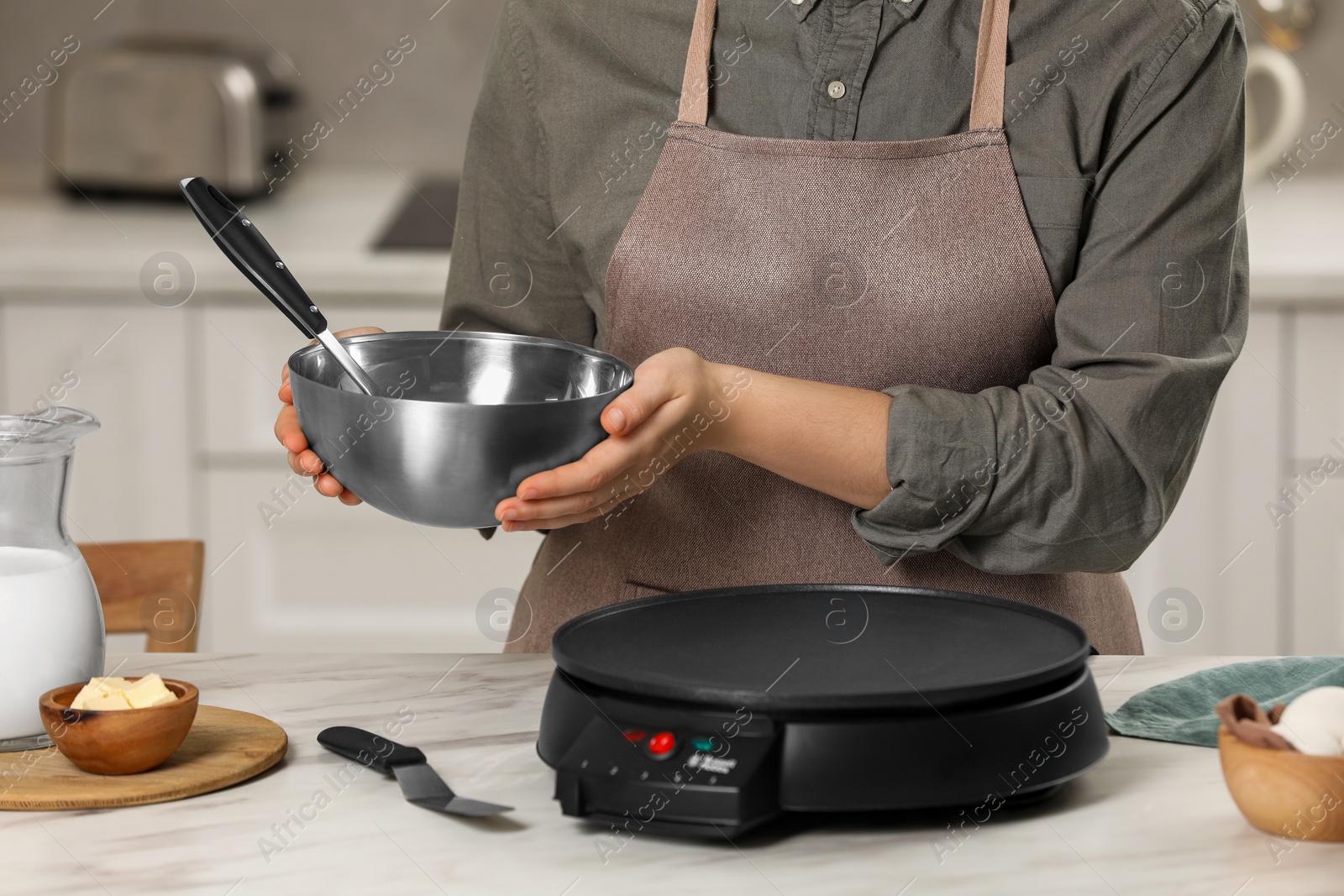 Photo of Woman cooking delicious crepes in kitchen, closeup