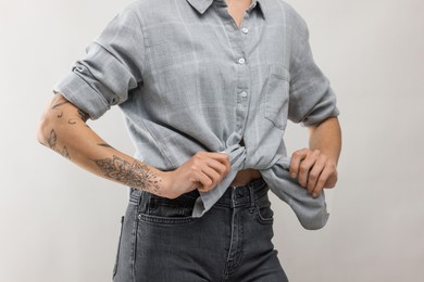 Photo of Woman with cool tattoos on light background, closeup