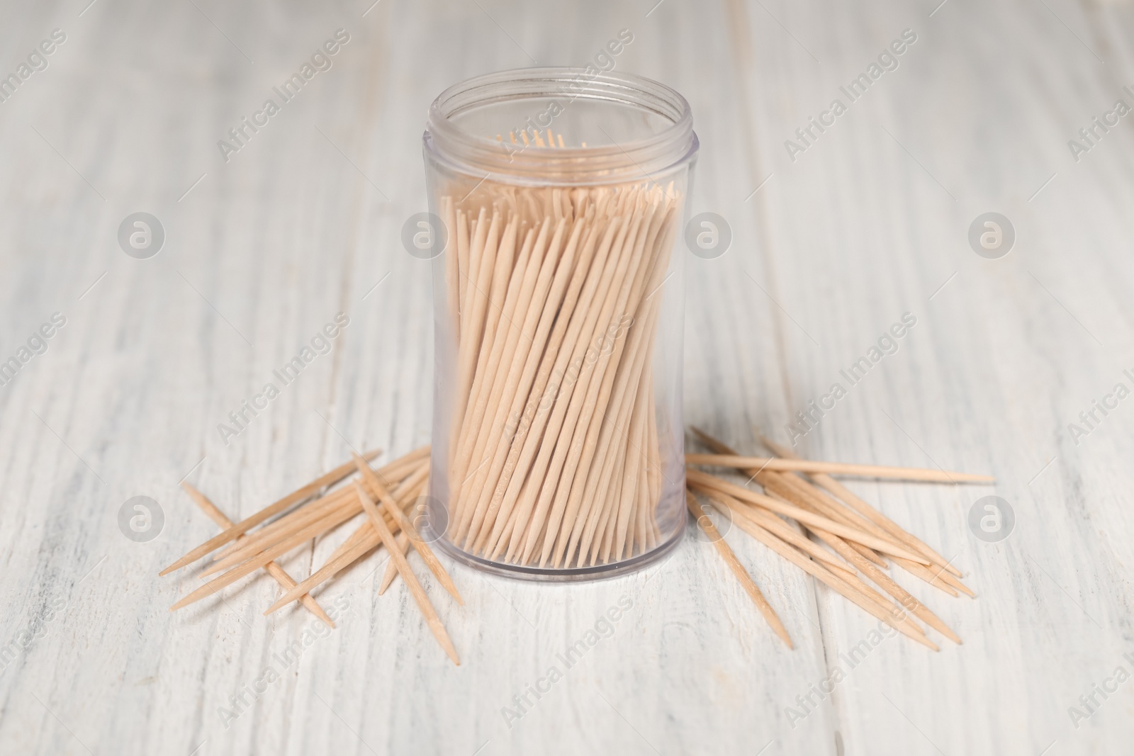Photo of Disposable toothpicks and holder on white wooden background
