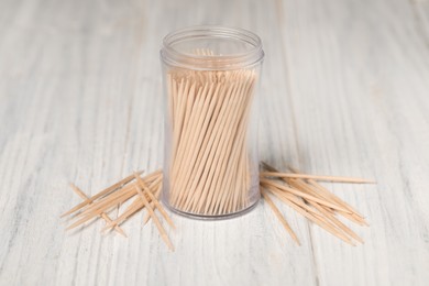 Disposable toothpicks and holder on white wooden background