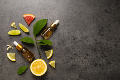 Photo of Flat lay composition with bottles of citrus essential oil on grey background. Space for text