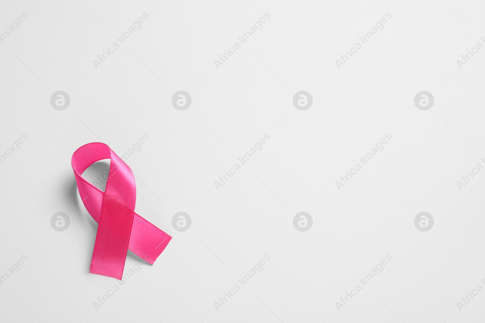 Photo of Pink ribbon on white background, top view and space for text. Breast cancer awareness