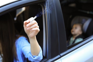 Mother with cigarette and child in car, closeup. Don't smoke near kids