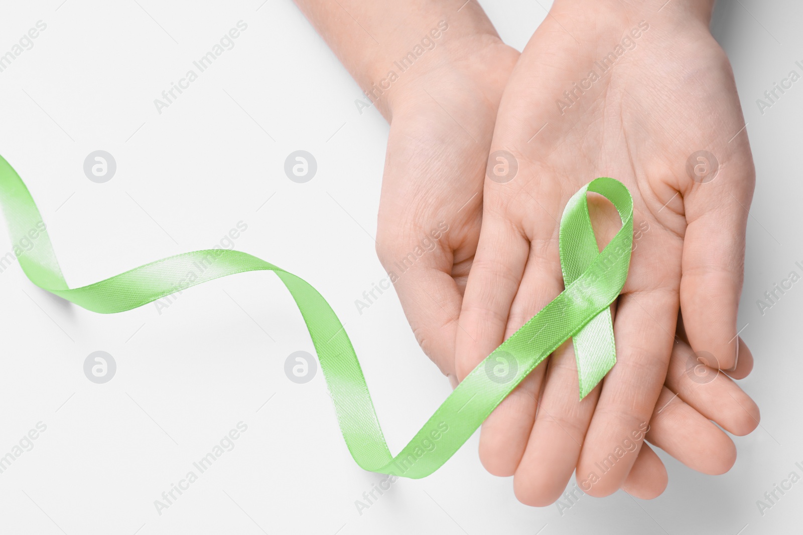 Photo of World Mental Health Day. Woman holding green ribbon on white background, top view