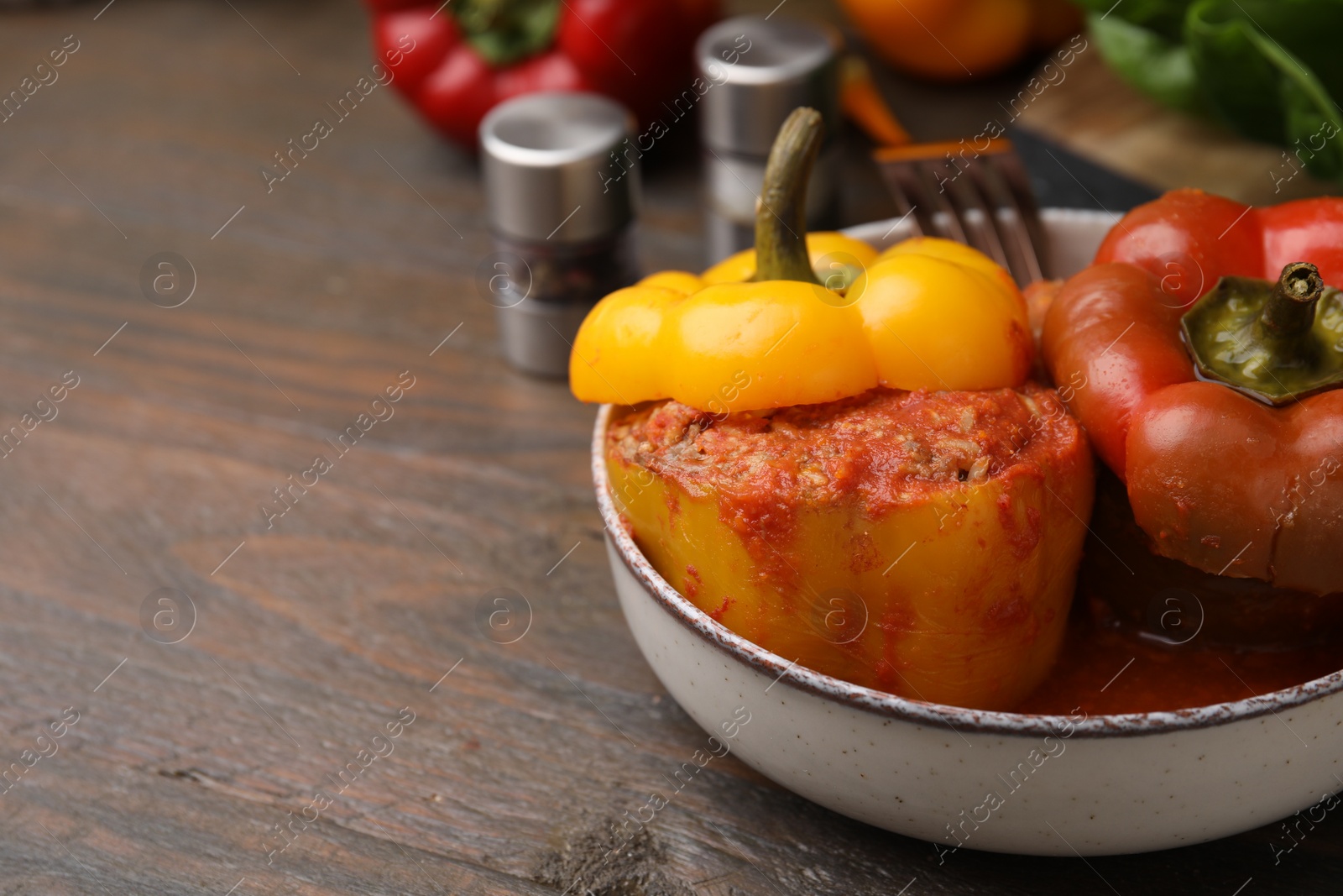 Photo of Delicious stuffed bell peppers served on wooden table, closeup. Space for text