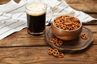 Photo of Delicious pretzel crackers and glass of beer on wooden table