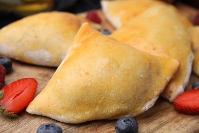 Delicious samosas and berries on wooden board, closeup