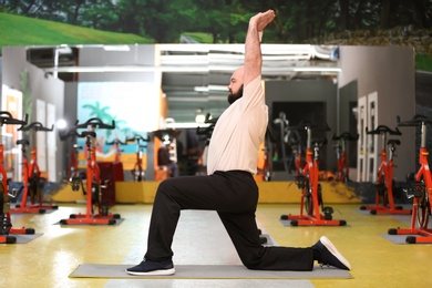 Overweight man doing exercise in gym