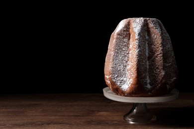 Photo of Delicious Pandoro cake decorated with powdered sugar on wooden table, space for text. Traditional Italian pastry