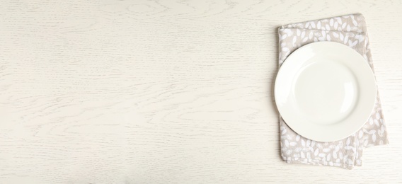 Photo of Empty plate and napkin on white wooden table, top view. Space for text