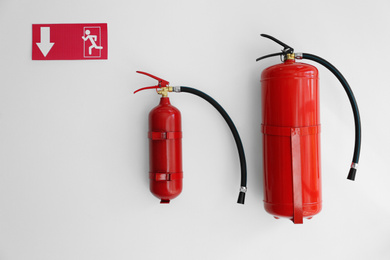 Photo of Fire extinguishers and emergency exit sign on white wall