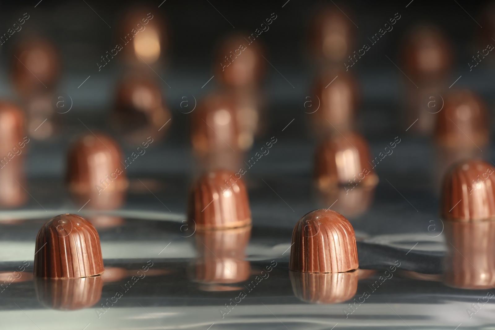 Photo of Many delicious chocolate candies on production line, closeup