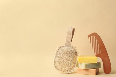 Natural loofah, bamboo hair comb and soap bars on beige background, space for text. Conscious consumption