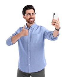 Photo of Smiling man taking selfie with smartphone and showing thumbs up on white background