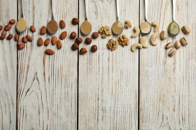 Photo of Jars with butters made of different nuts and ingredients on white wooden table, flat lay. Space for text