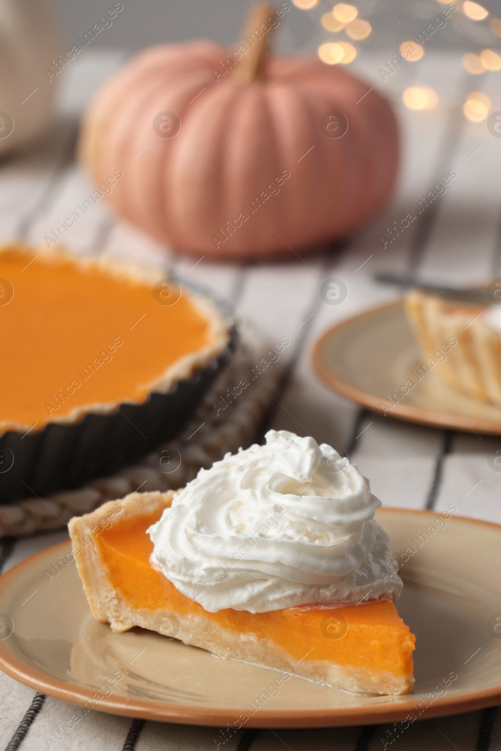 Photo of Piece of fresh homemade pumpkin pie with whipped cream on table