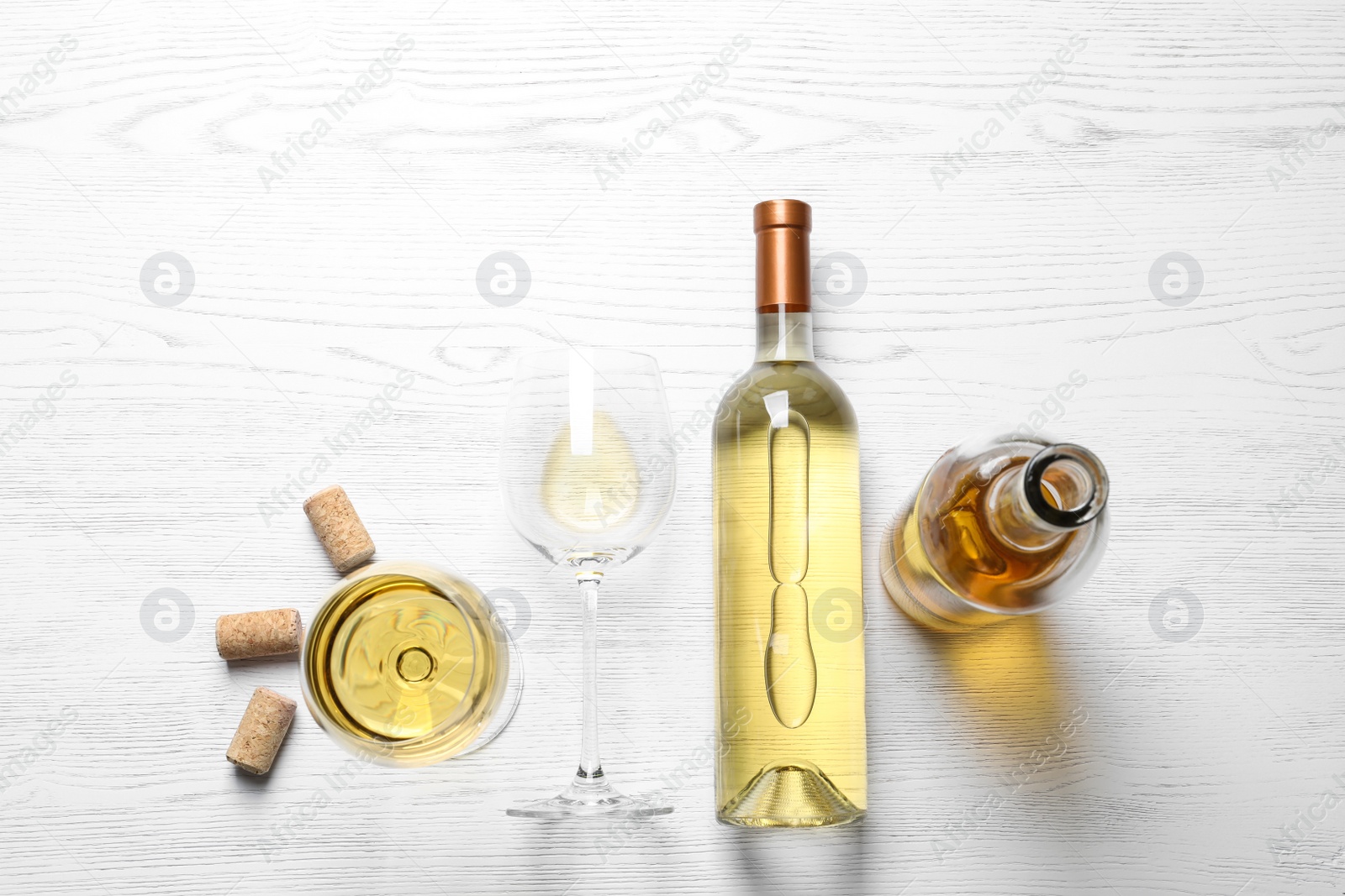 Photo of Glasses and bottles with white wine on wooden background, flat lay