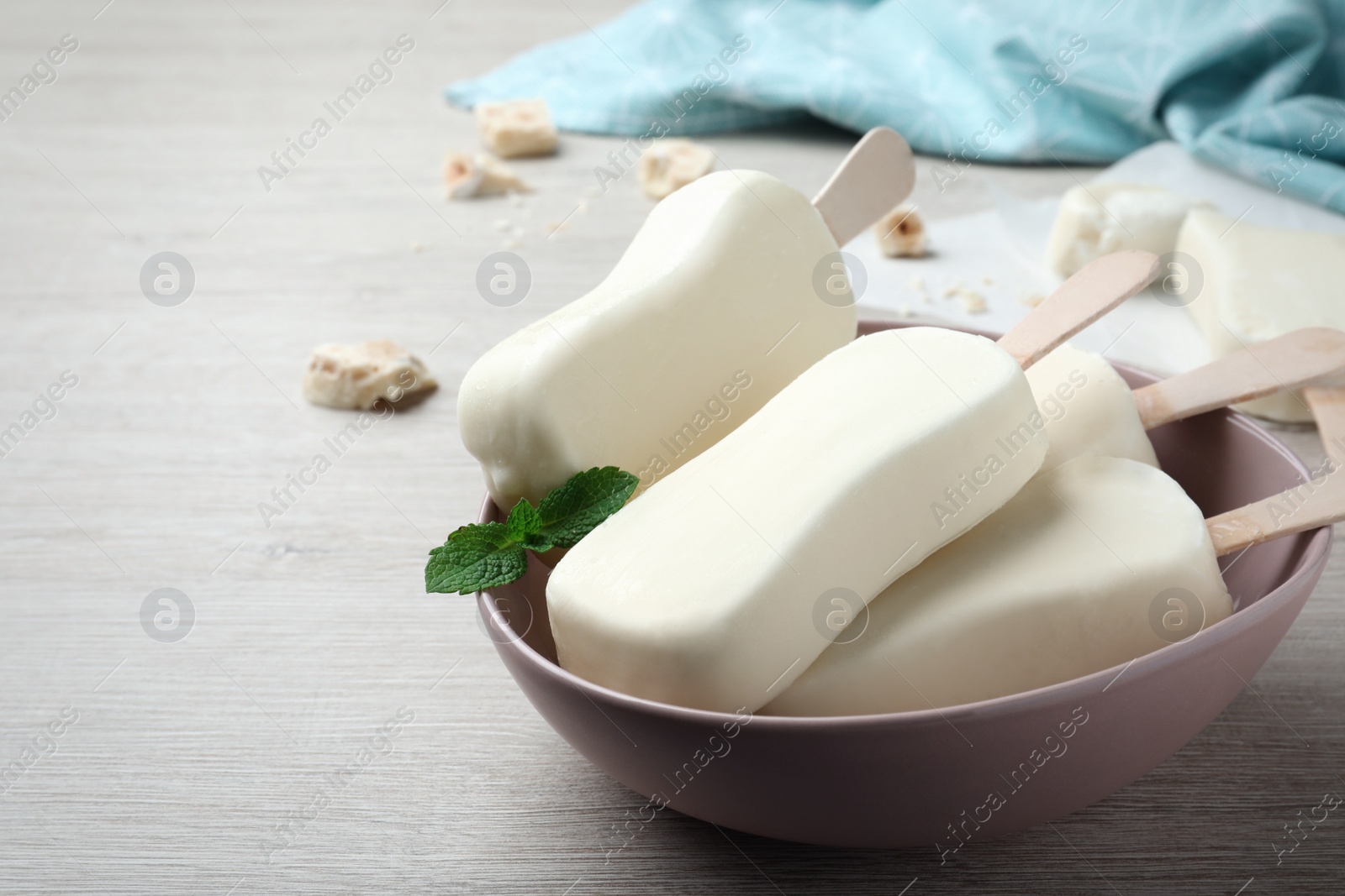 Photo of Delicious glazed ice cream bars, chocolate and mint on white wooden table. Space for text