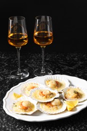 Photo of Fried scallops in shells and wine on black textured table