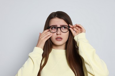 Photo of Young woman suffering from eyestrain on light background