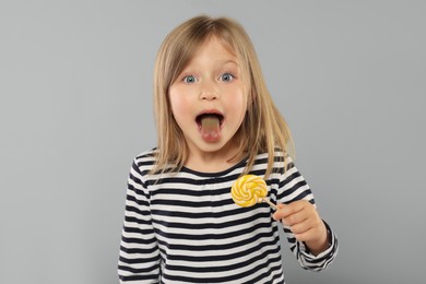 Photo of Portrait of cute girl with lollipop on light grey background