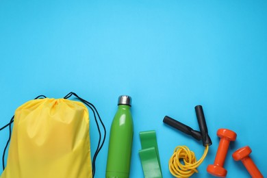 Photo of Yellow drawstring bag and sports equipment on light blue background, flat lay. Space for text