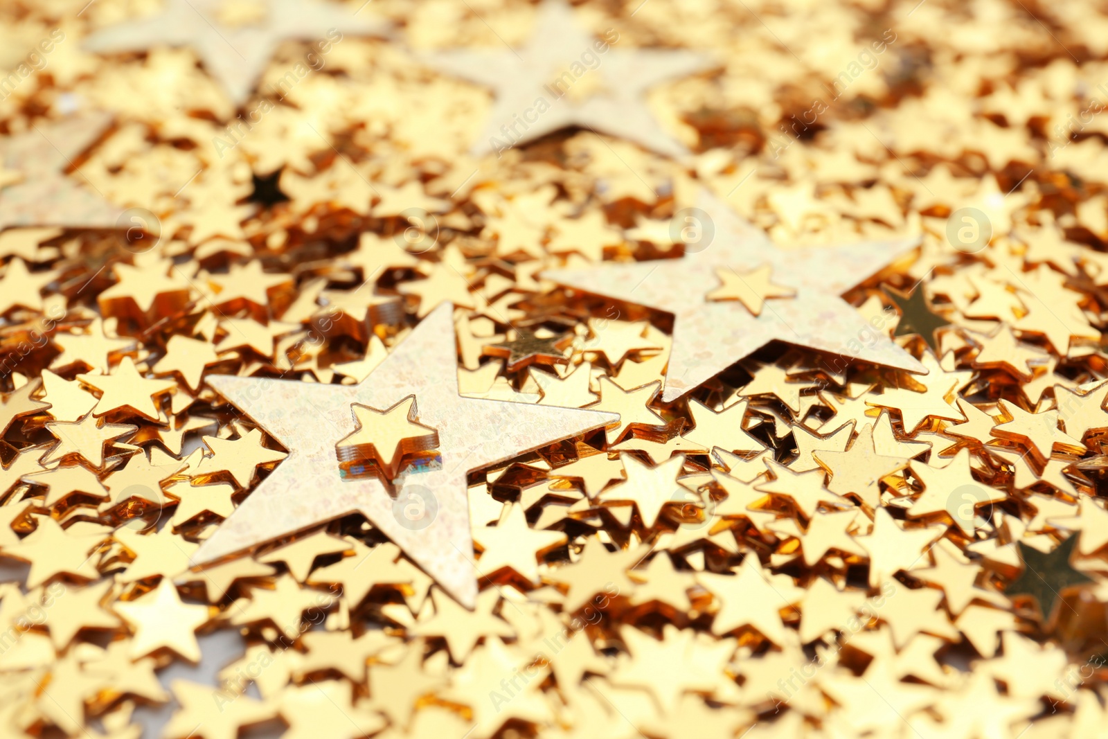 Photo of Golden confetti stars as background, closeup. Christmas celebration