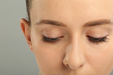 Photo of Woman with long eyelashes after mascara applying against grey background, closeup