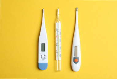 Photo of Different thermometers on yellow background, flat lay