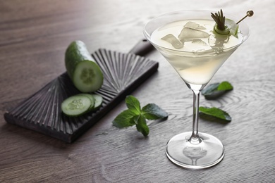 Photo of Glass of tasty cucumber martini and ingredients on wooden table