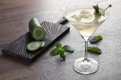 Glass of tasty cucumber martini and ingredients on wooden table