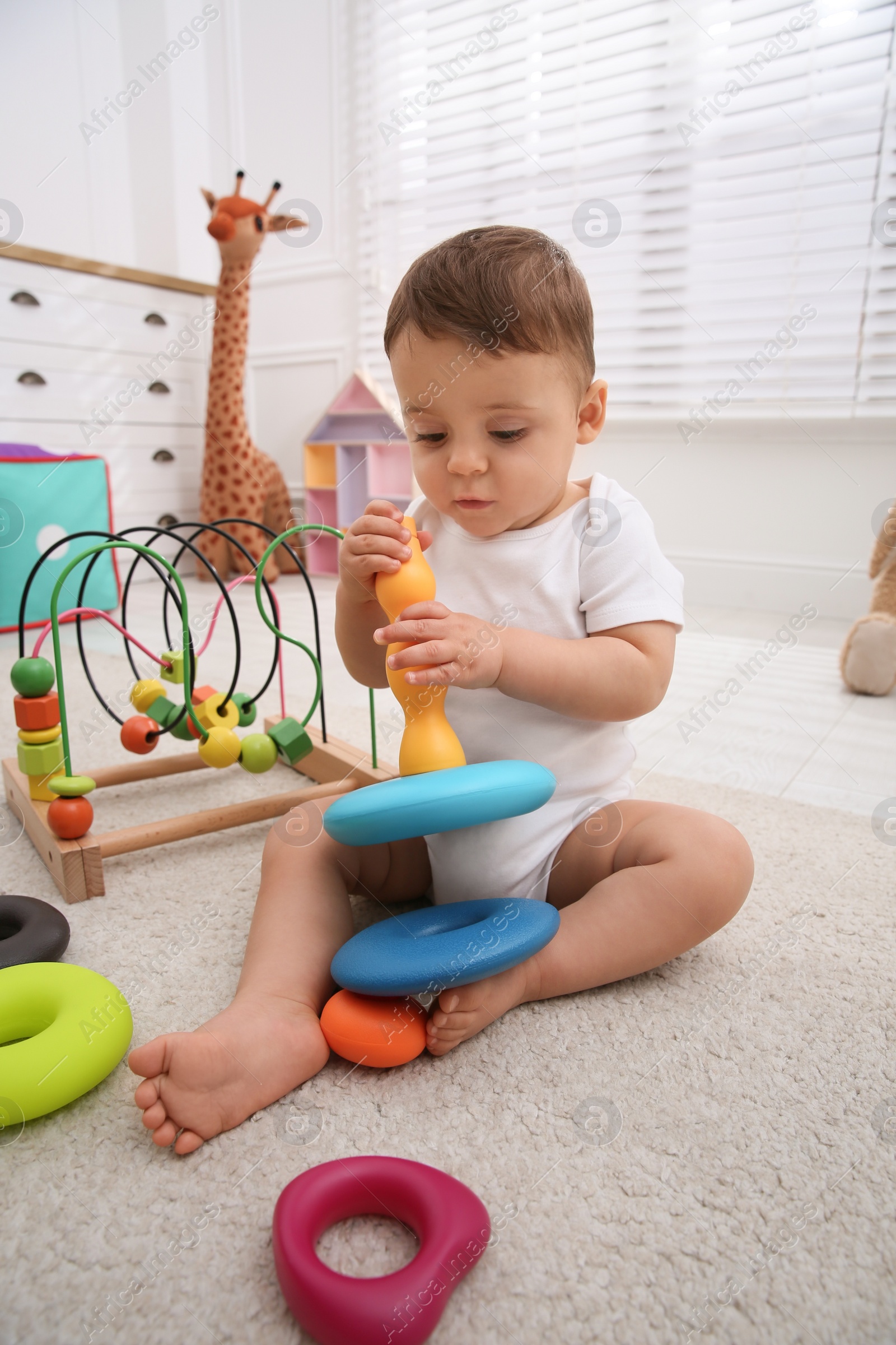 Photo of Cute baby boy playing with toys on floor at home