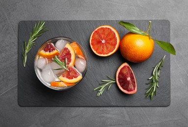 Photo of Delicious refreshing drink with sicilian orange and rosemary near fresh ingredients on grey table, flat lay